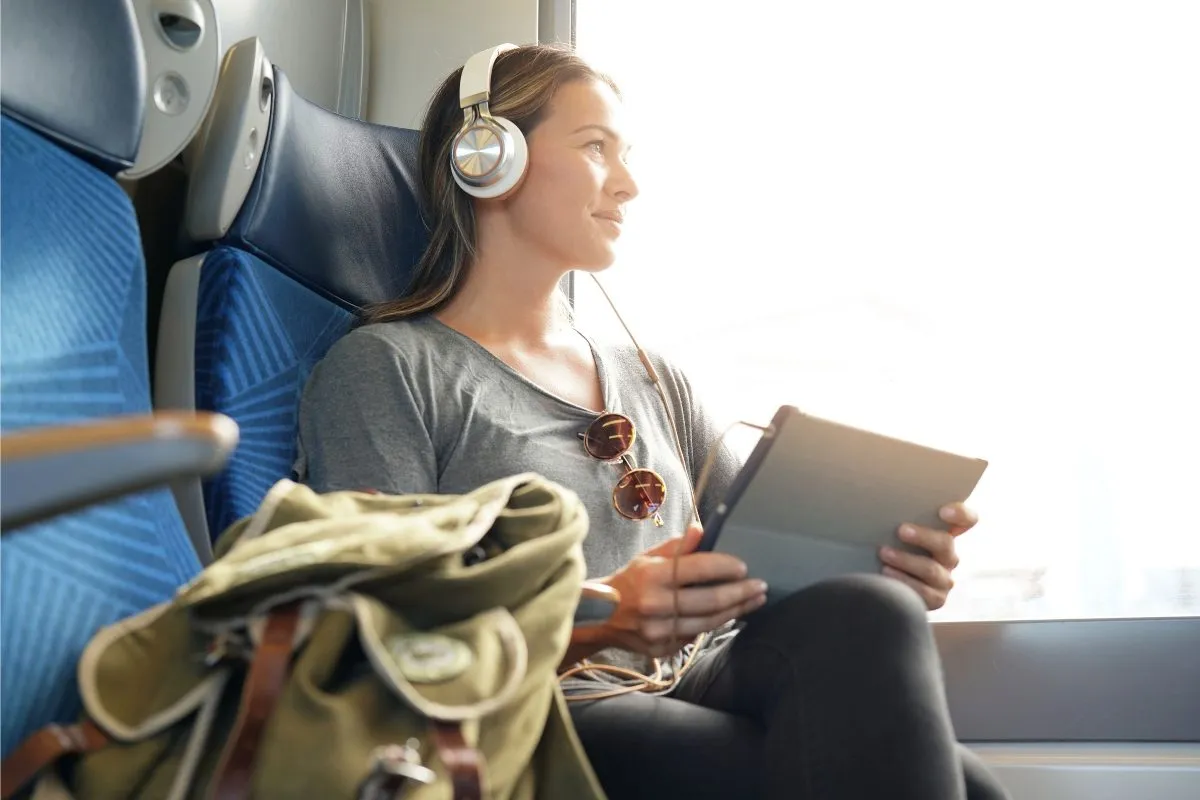 Frau mit Noise-Cancelling-Kopfhörern während einer Zugfahrt